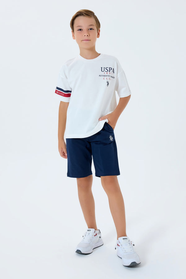U.S. Polo Assn. bijeli komplet majice s USPA printom i teget šorca s trakom na rukavu za dječake